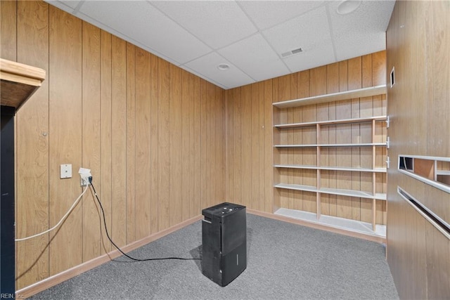 miscellaneous room featuring a paneled ceiling, wooden walls, and carpet