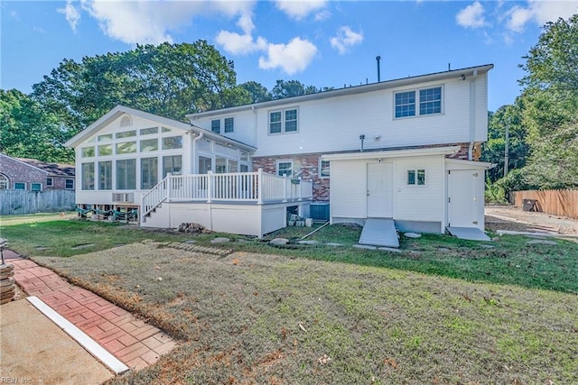 back of house with a wooden deck, a sunroom, and a yard