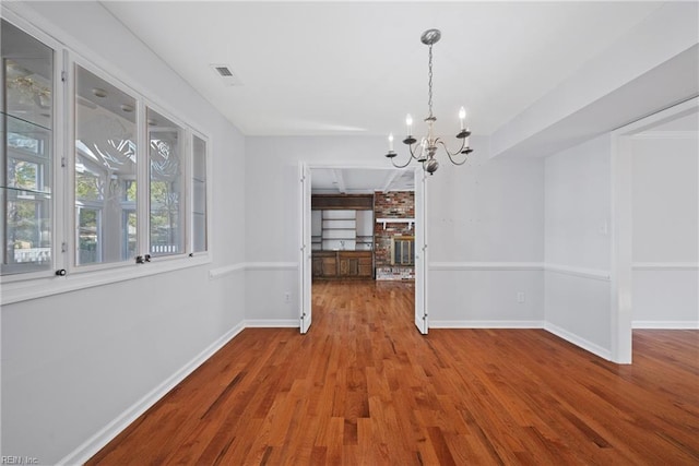 unfurnished dining area featuring wood-type flooring and an inviting chandelier