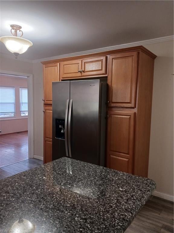 kitchen with hardwood / wood-style floors, stainless steel fridge, crown molding, and dark stone counters