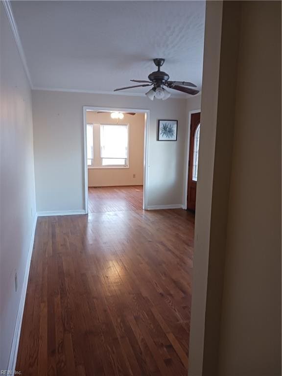 empty room featuring ceiling fan, ornamental molding, and dark wood-type flooring