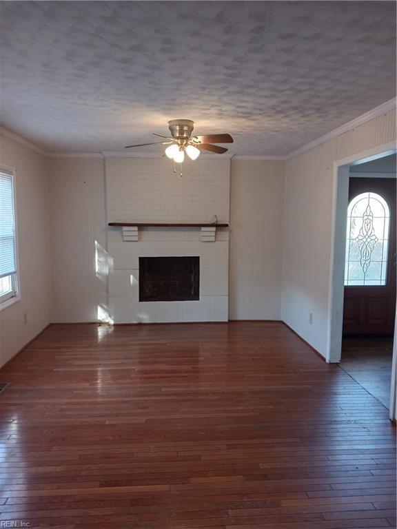 unfurnished living room with a textured ceiling, dark hardwood / wood-style flooring, ceiling fan, and ornamental molding