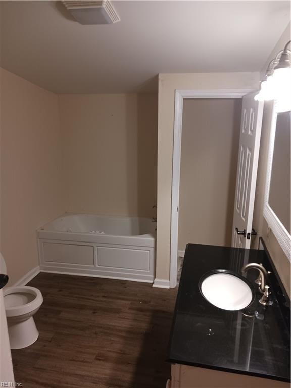 bathroom featuring a bathtub, vanity, hardwood / wood-style floors, and toilet