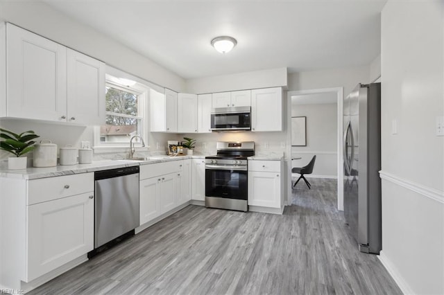 kitchen featuring light wood-type flooring, white cabinetry, sink, and appliances with stainless steel finishes