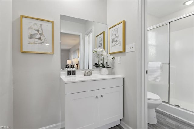 bathroom with hardwood / wood-style flooring, vanity, toilet, and a shower with door