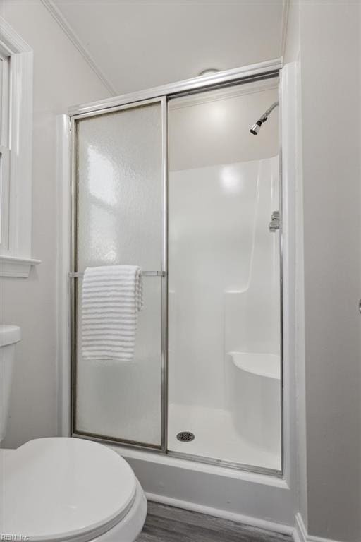 bathroom with hardwood / wood-style floors, a shower with shower door, and toilet