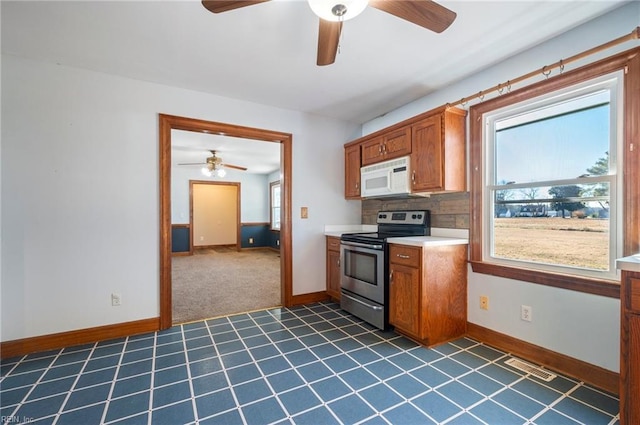 kitchen with dark colored carpet, ceiling fan, stainless steel electric range oven, and tasteful backsplash