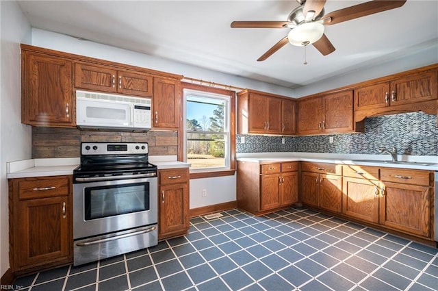 kitchen with backsplash, ceiling fan, sink, and stainless steel range with electric stovetop