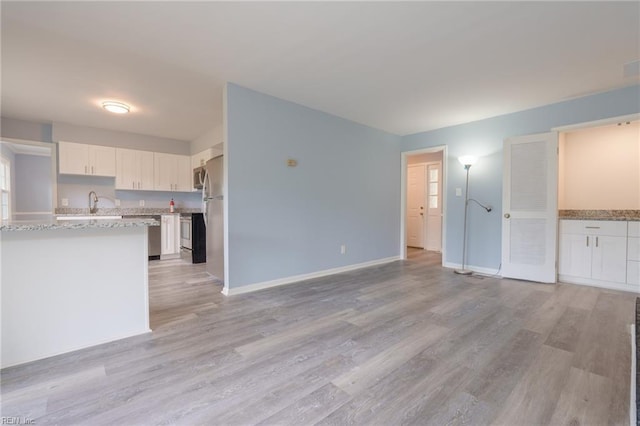 unfurnished living room with light hardwood / wood-style flooring and sink