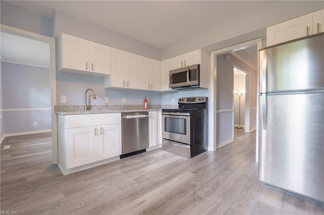 kitchen with sink, light hardwood / wood-style flooring, white cabinets, and appliances with stainless steel finishes