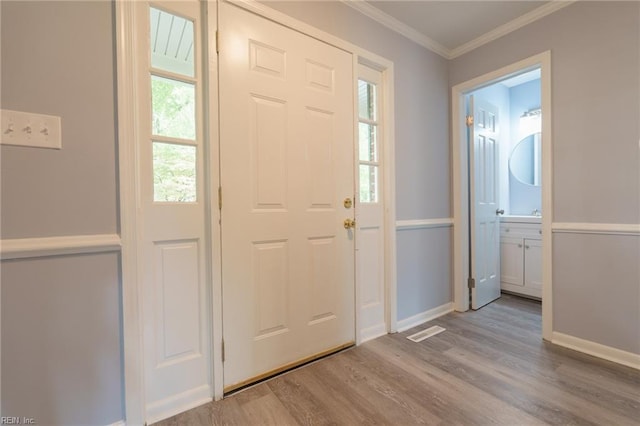 entrance foyer featuring ornamental molding and light hardwood / wood-style flooring