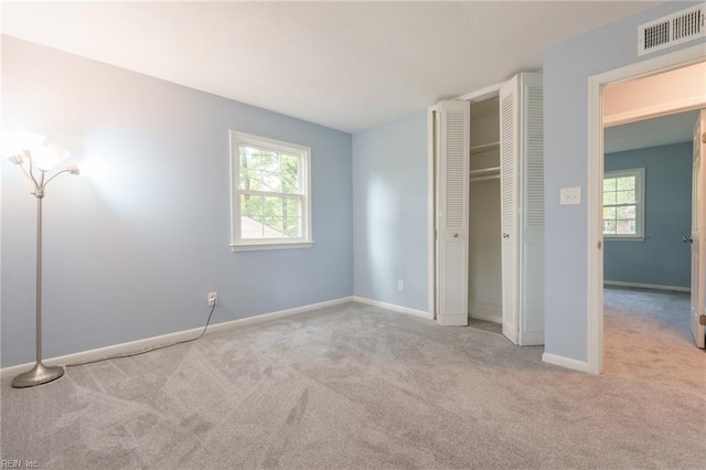 unfurnished bedroom with a closet, light carpet, and multiple windows