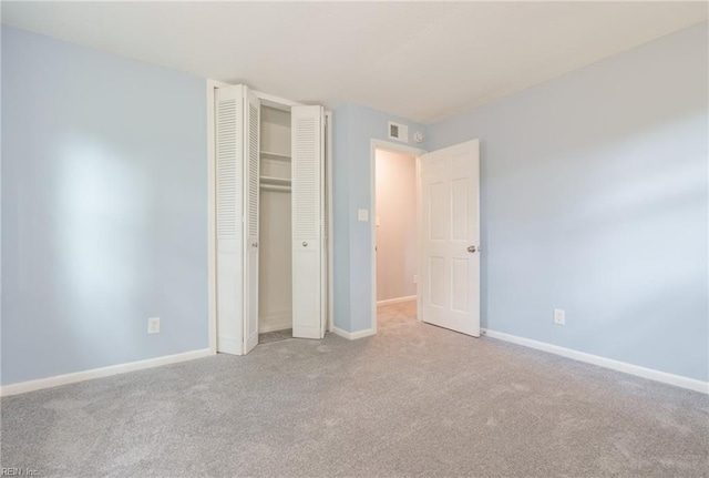 unfurnished bedroom with light colored carpet and a closet