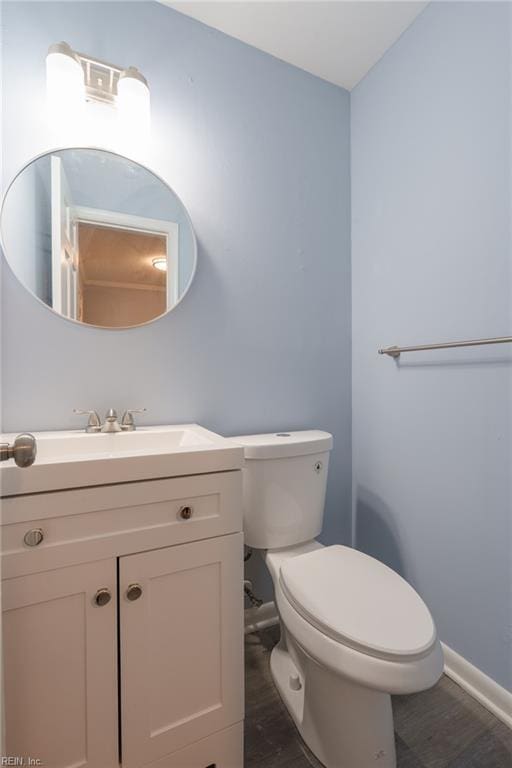 bathroom with wood-type flooring, vanity, and toilet