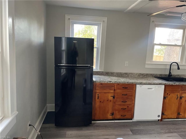 kitchen with dishwasher, black refrigerator, sink, light hardwood / wood-style flooring, and ceiling fan