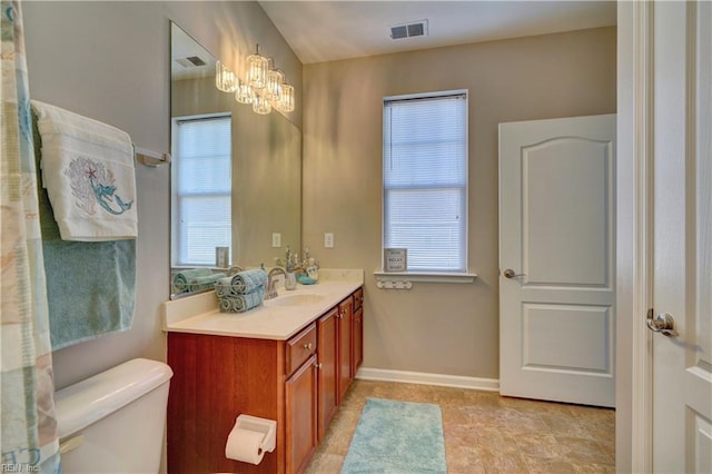 bathroom featuring plenty of natural light, vanity, an inviting chandelier, and toilet