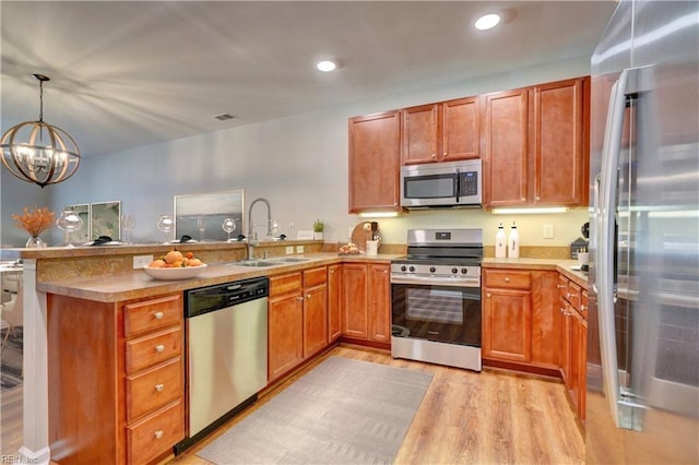 kitchen featuring appliances with stainless steel finishes, sink, decorative light fixtures, light hardwood / wood-style flooring, and an inviting chandelier