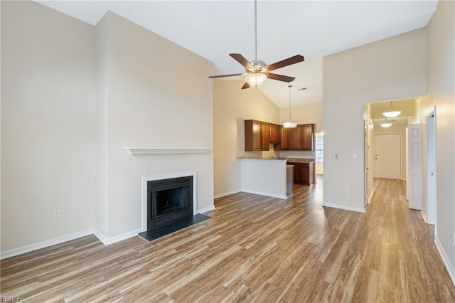 unfurnished living room with hardwood / wood-style flooring, ceiling fan, and high vaulted ceiling