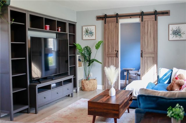 living room with a barn door and light hardwood / wood-style floors