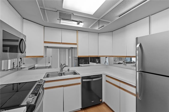 kitchen with appliances with stainless steel finishes, white cabinetry, and sink