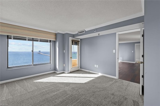 unfurnished room featuring a water view, carpet floors, a textured ceiling, and ornamental molding