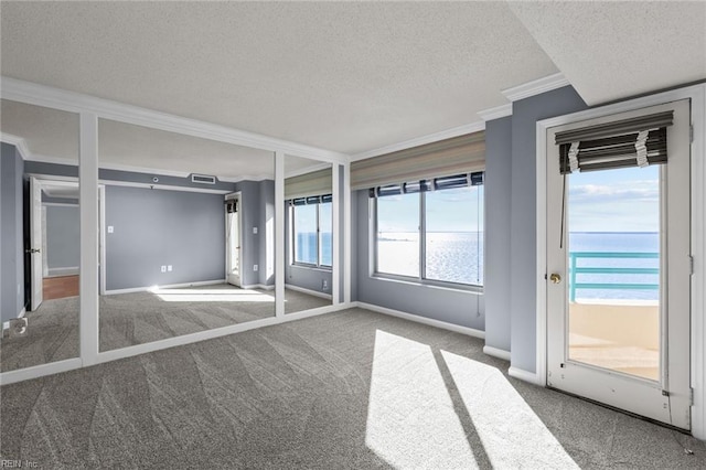 unfurnished bedroom with carpet, a textured ceiling, a water view, and ornamental molding