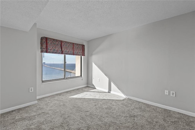 carpeted empty room with a textured ceiling and a water view