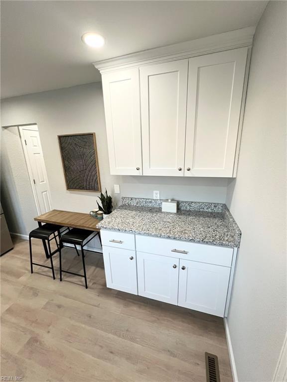 kitchen with light stone counters, light hardwood / wood-style flooring, and white cabinets