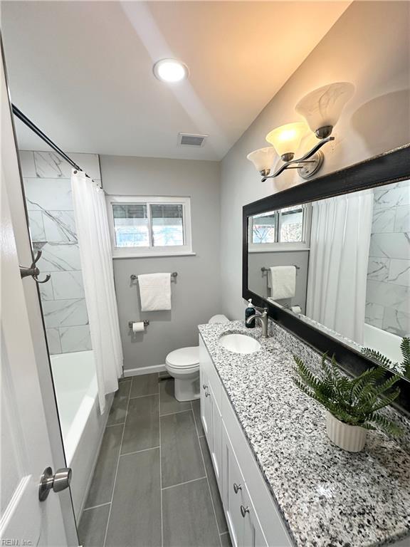 full bathroom featuring vanity, a healthy amount of sunlight, toilet, and shower / bath combo