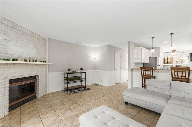 tiled living room featuring ceiling fan and a fireplace