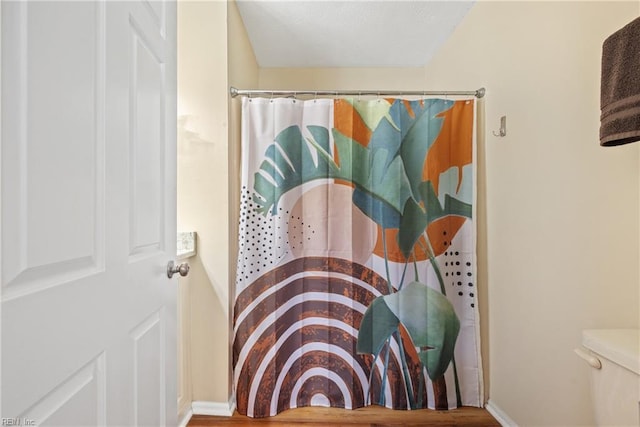 bathroom featuring wood-type flooring, toilet, and walk in shower