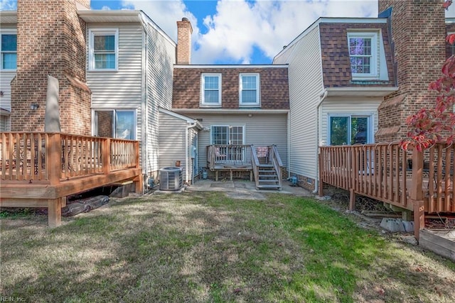 rear view of house with central AC unit, a wooden deck, and a lawn