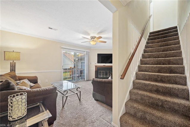 carpeted living room with ceiling fan and ornamental molding