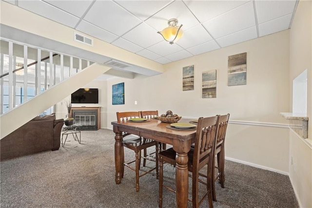 carpeted dining room featuring a drop ceiling