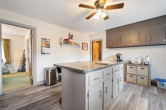 kitchen with gray cabinets, ceiling fan, a center island, and light wood-type flooring