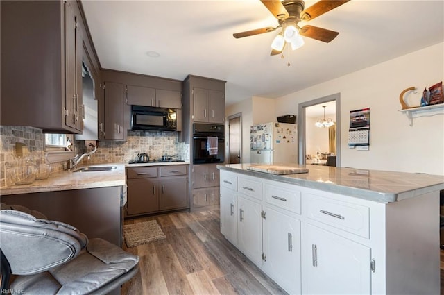 kitchen featuring sink, wood-type flooring, decorative backsplash, white cabinets, and black appliances