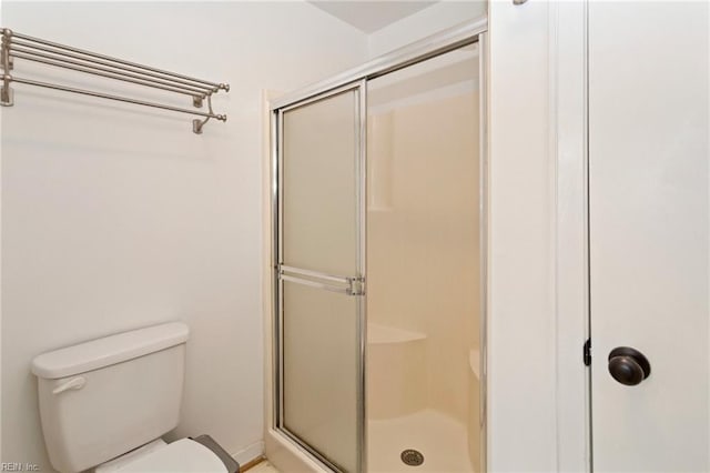 bathroom featuring toilet and a shower with shower door