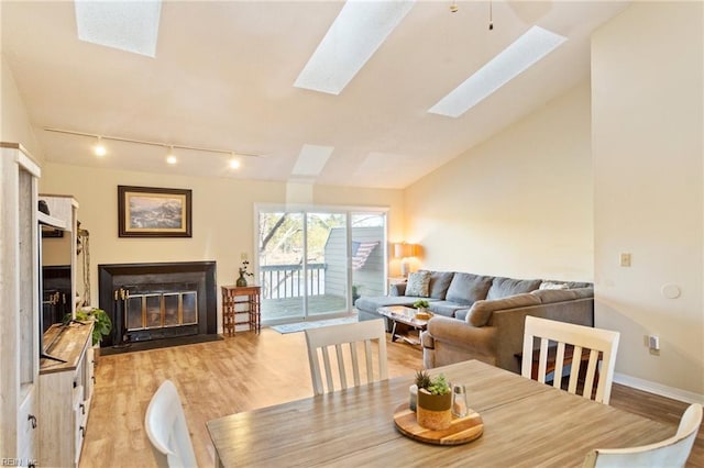 dining space featuring lofted ceiling with skylight and light hardwood / wood-style floors