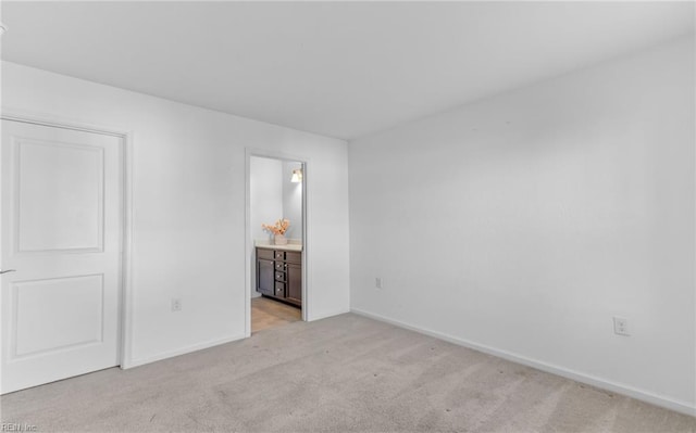 unfurnished bedroom featuring ensuite bath and light carpet