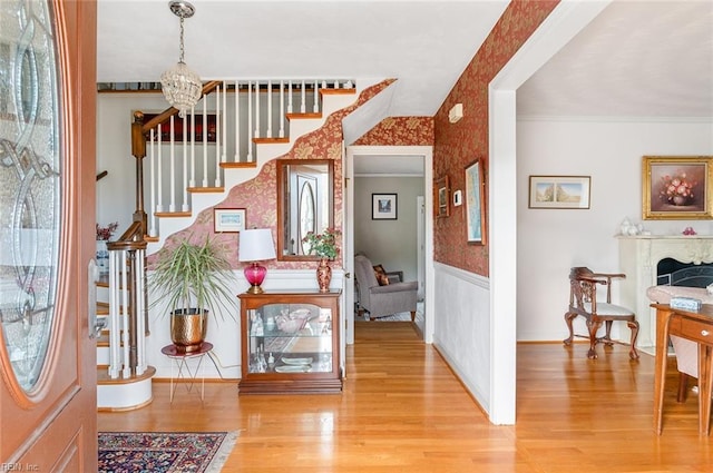 entrance foyer featuring crown molding, hardwood / wood-style floors, and an inviting chandelier