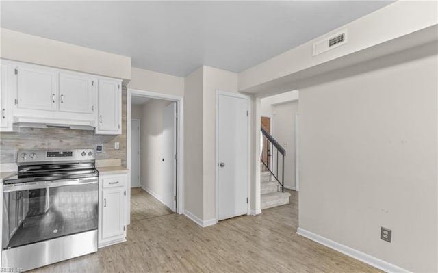 kitchen with decorative backsplash, light hardwood / wood-style floors, white cabinetry, and stainless steel range with electric stovetop