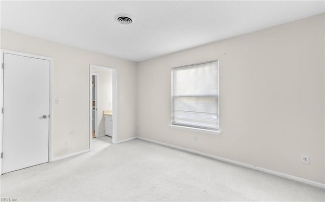 unfurnished bedroom with connected bathroom and light colored carpet