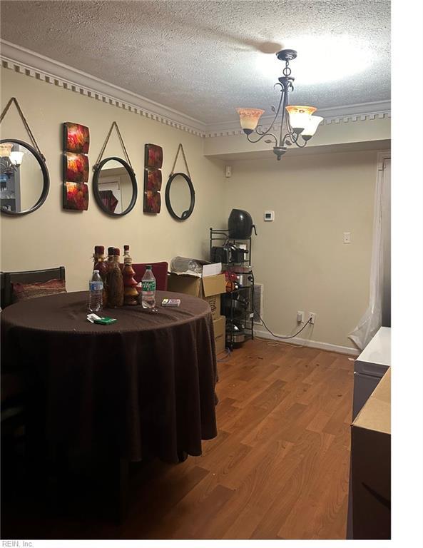 interior space featuring crown molding, an inviting chandelier, hardwood / wood-style floors, a textured ceiling, and decorative light fixtures