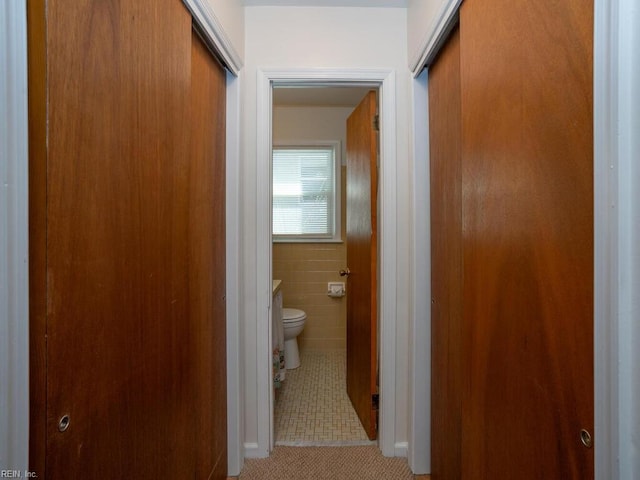 corridor with light tile patterned floors and tile walls