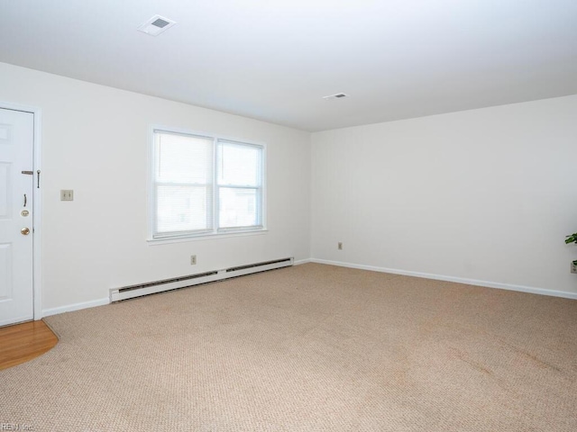 spare room with light carpet and a baseboard heating unit