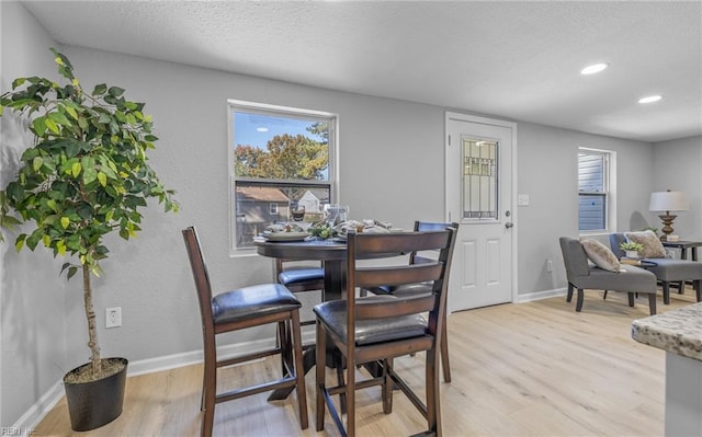 dining area featuring light hardwood / wood-style flooring and a textured ceiling