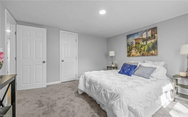 bedroom with light colored carpet and a textured ceiling