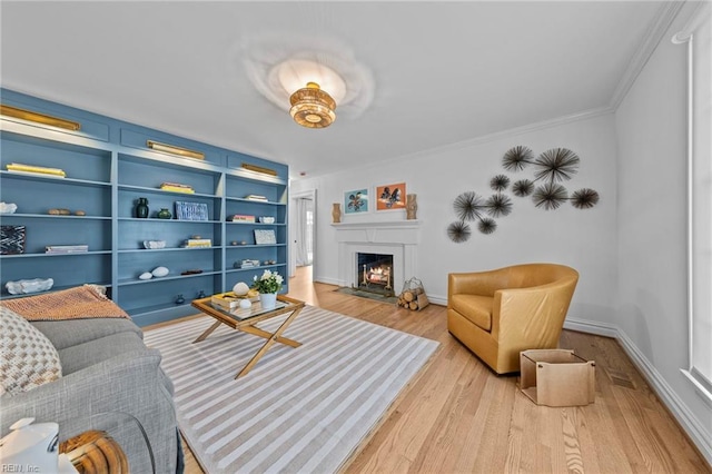 living room featuring built in shelves, ornamental molding, and light wood-type flooring