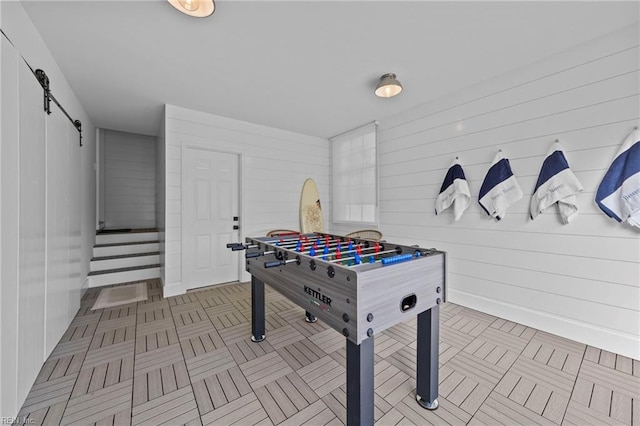 recreation room with a barn door and wooden walls