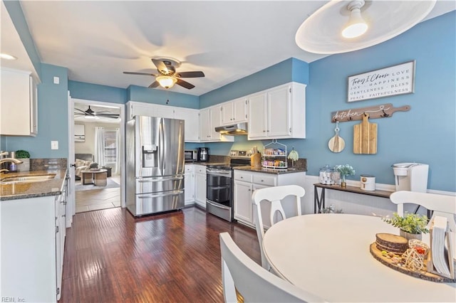 kitchen with appliances with stainless steel finishes, dark hardwood / wood-style flooring, dark stone counters, sink, and white cabinets